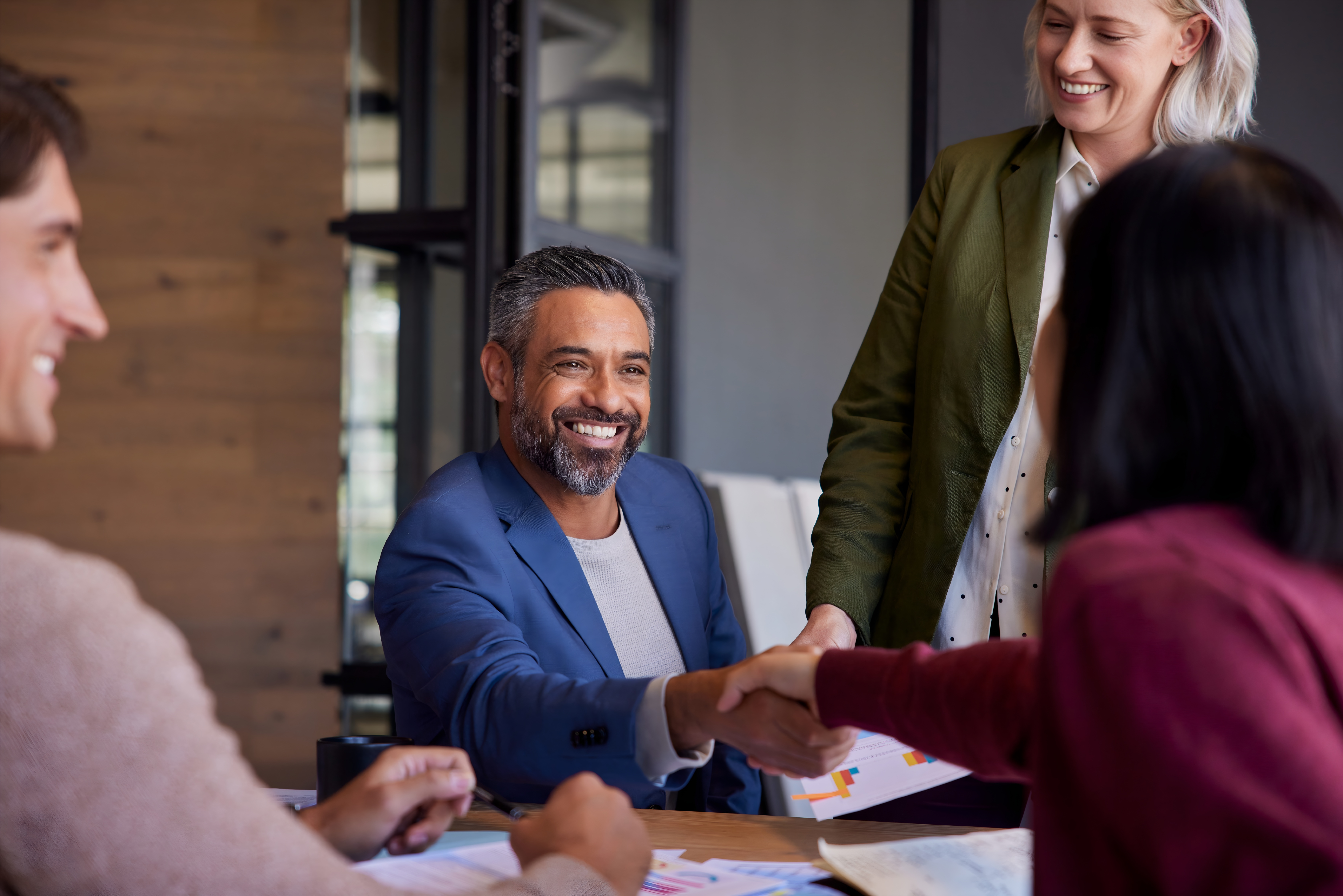 Business professionals shaking hands during a meeting, symbolizing partnership and collaboration